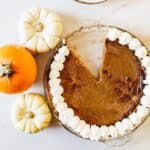 overhead view of pumpkin pie and pumpkins with one slice cut out