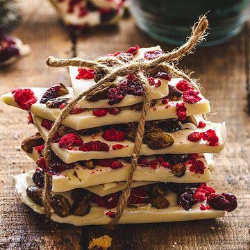 shut up of white chocolate bark wrapped in string with candle in background  Apple olive oil cake White Chocolate Bark THUMBNAIL 360x360