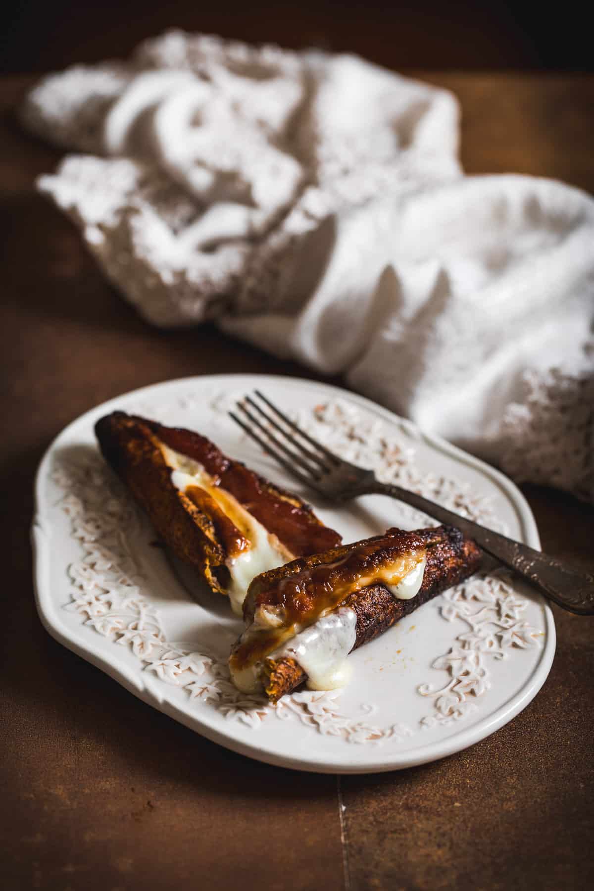 stuffed plantain cut in half on a plate with fork