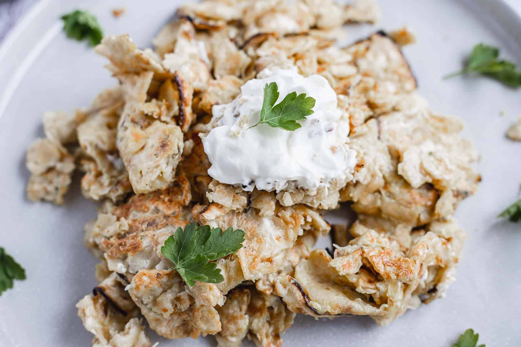 close up on small matzo brei serving with sour cream and parsley