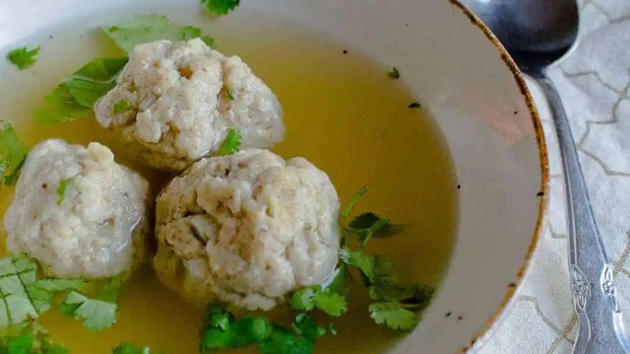close up on 3 matzo balls in soup