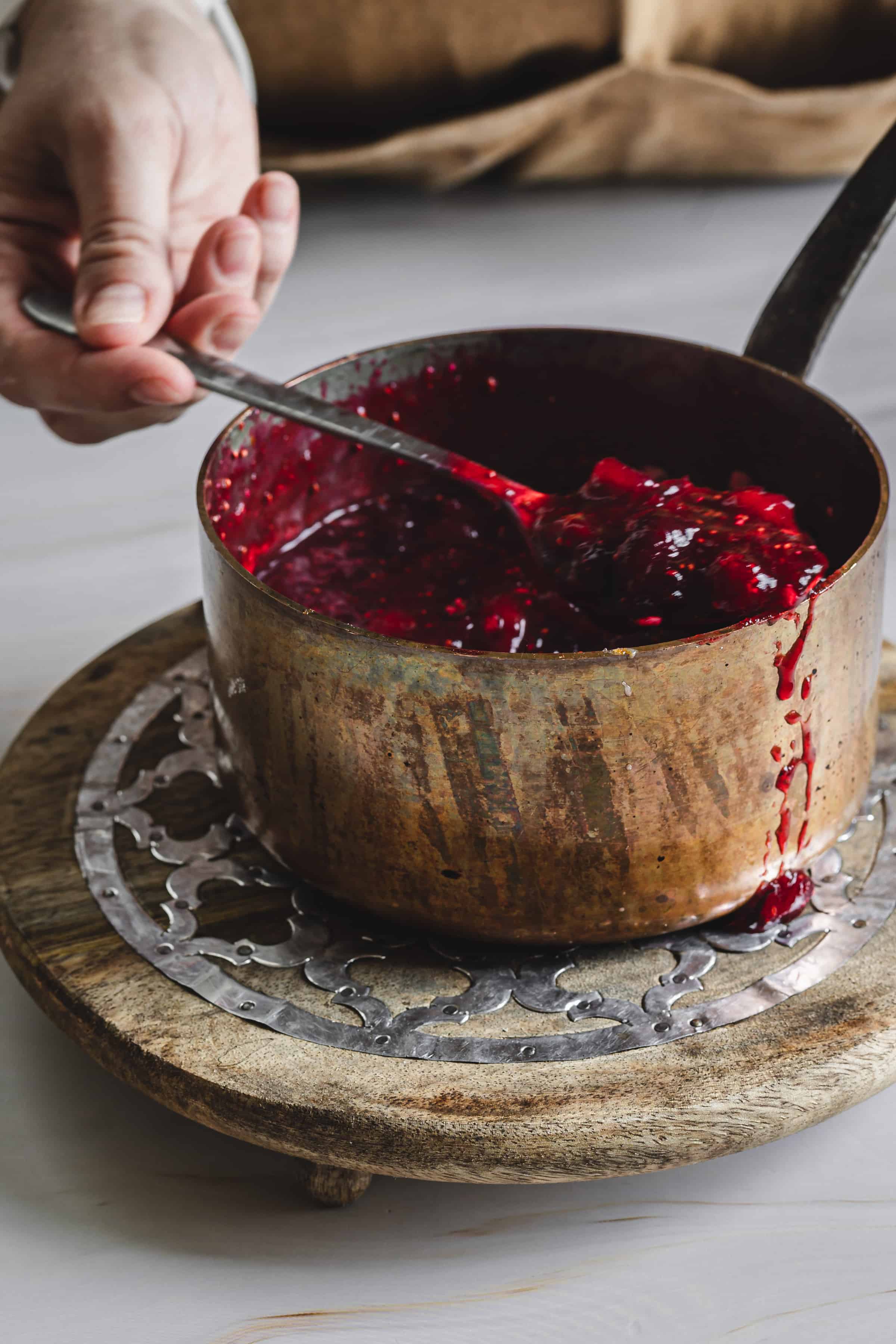 spooning cranberry topping out of the cooking pan