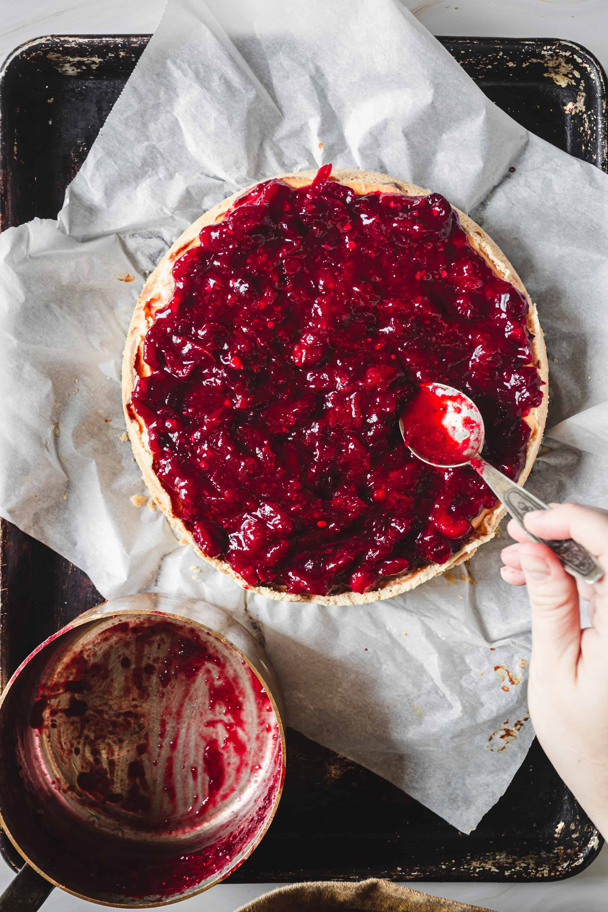 spooning the cranberry topping onto the cheesecake