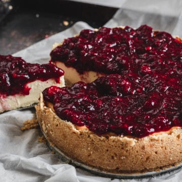 A cranberry cheesecake with a slice taken out of it.