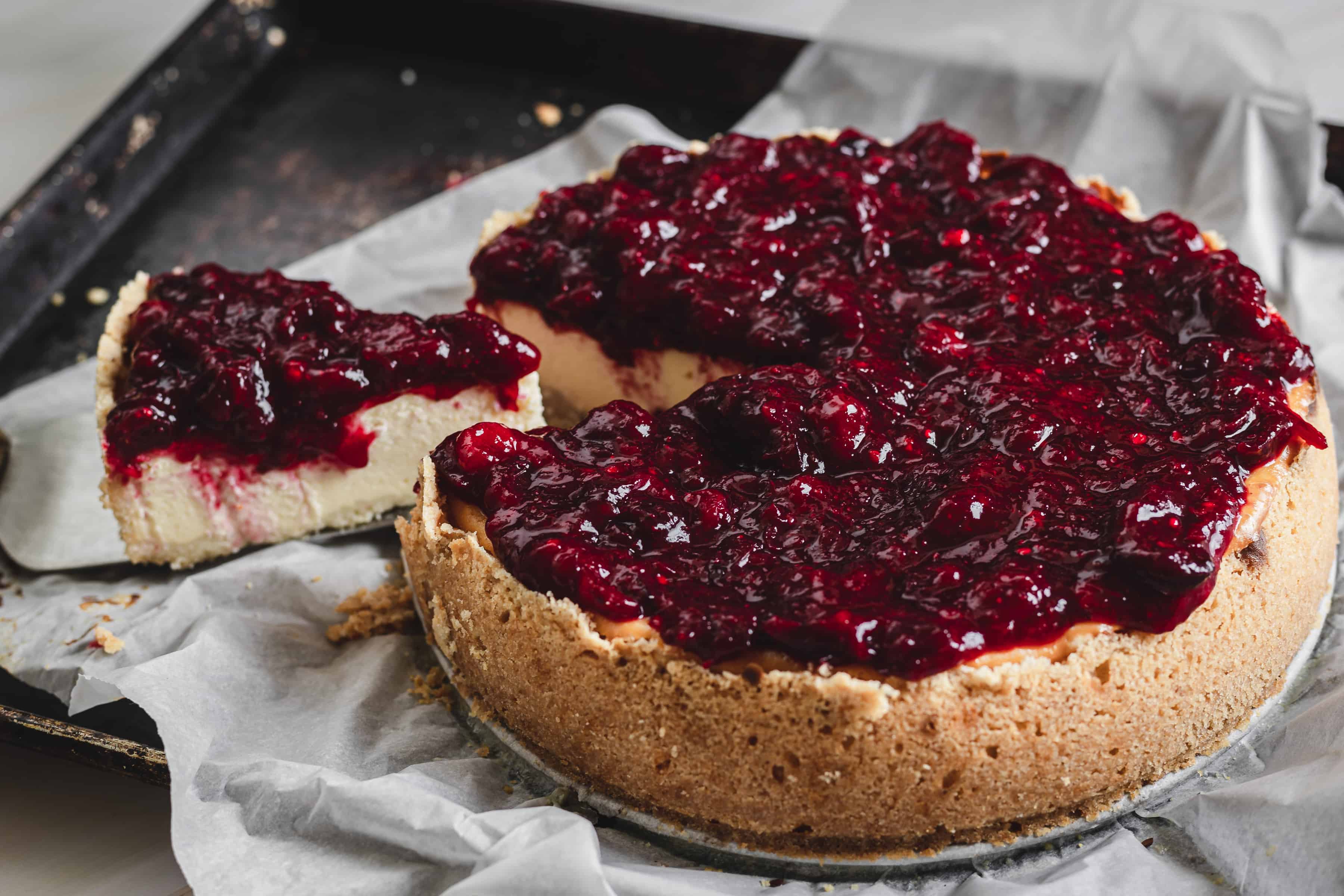 A cranberry cheesecake with a slice taken out of it.