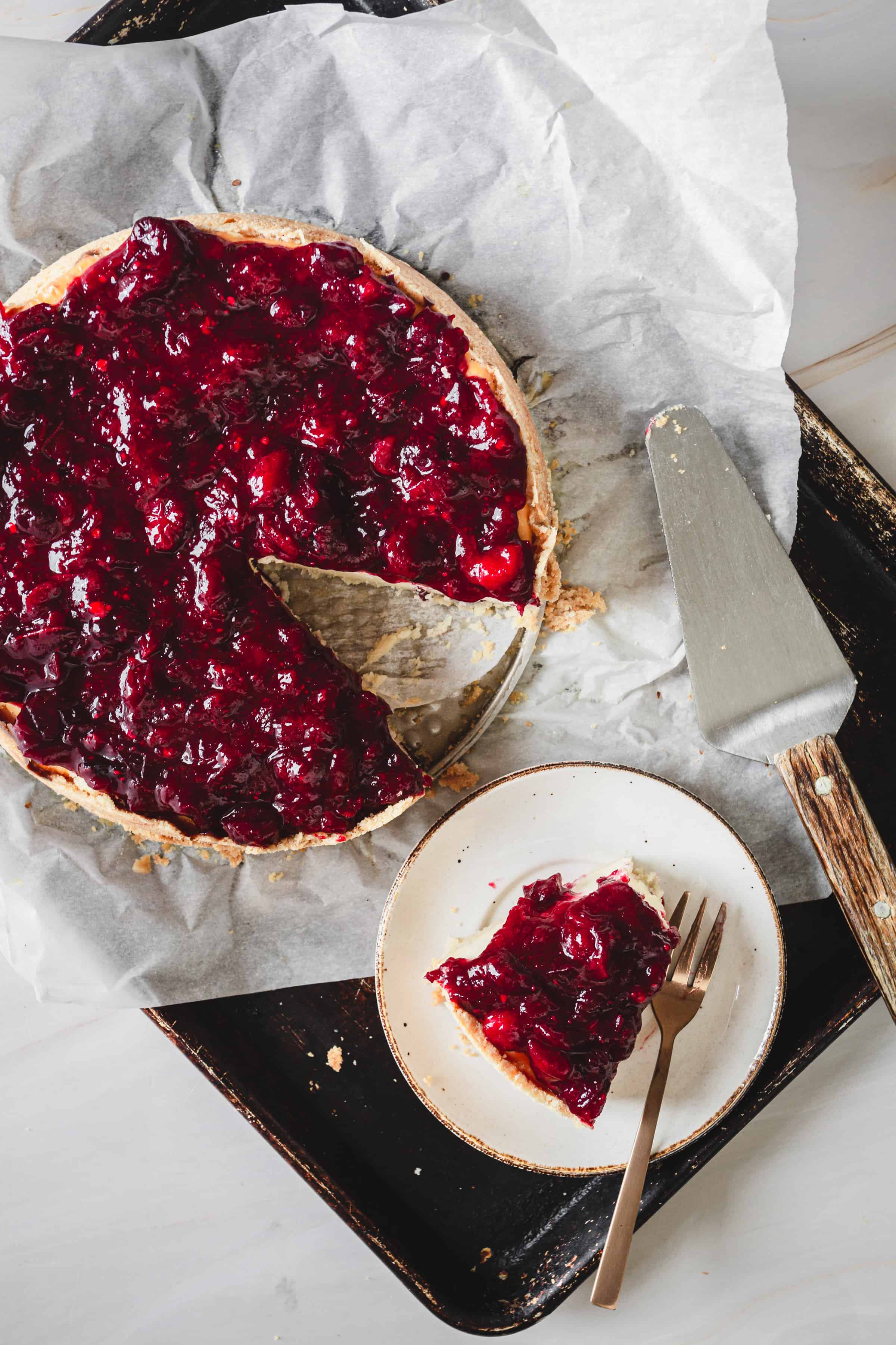 cheesecake with cranberry topping with a slice taken out and placed on a plate