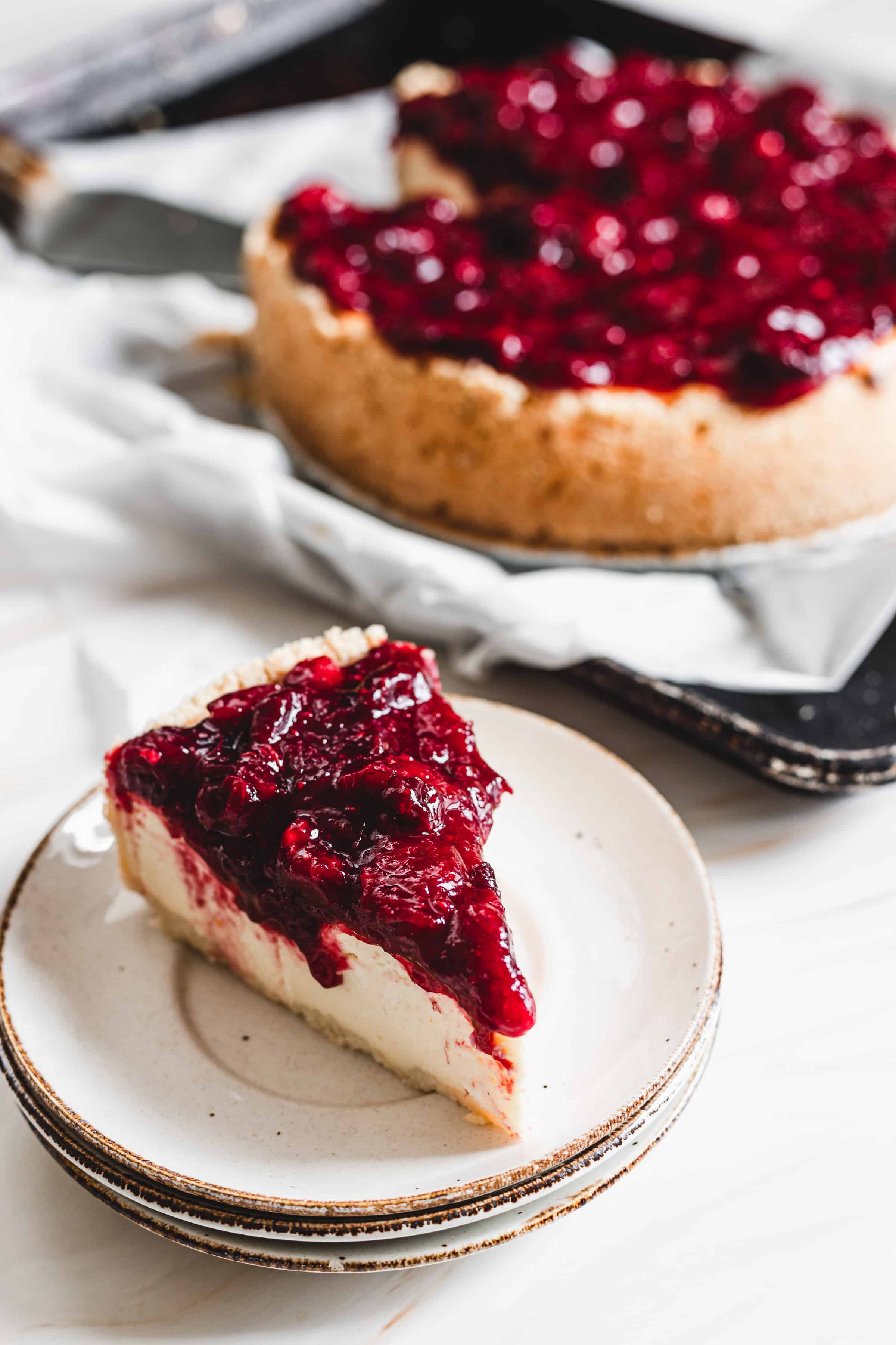 slice of cheesecake on a plate with cranberry topping