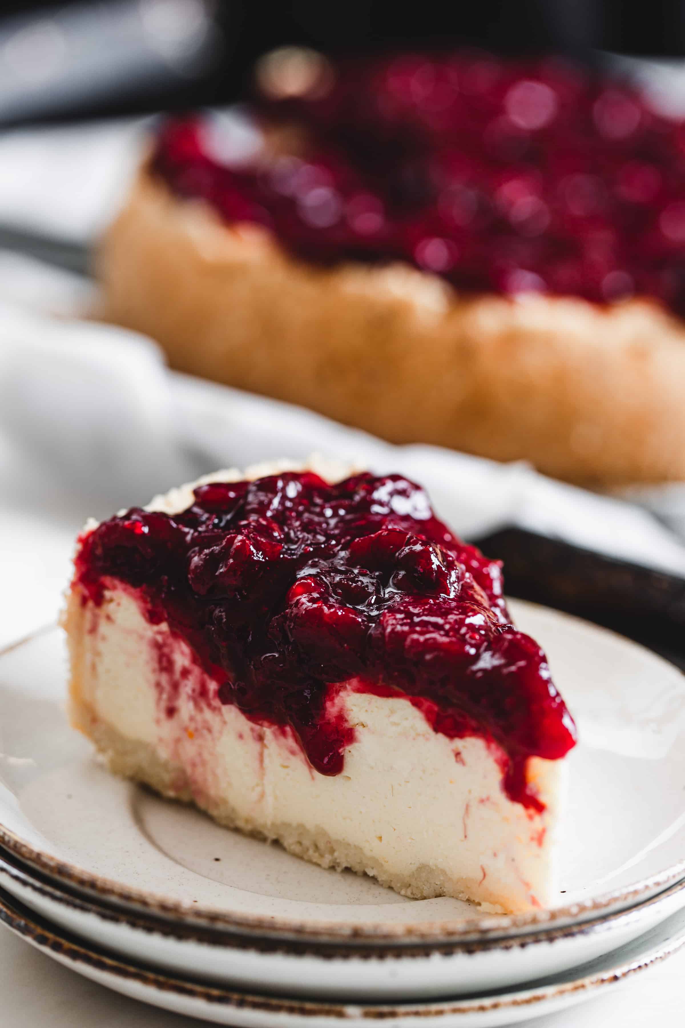 slice of cheesecake on a plate with cranberry topping