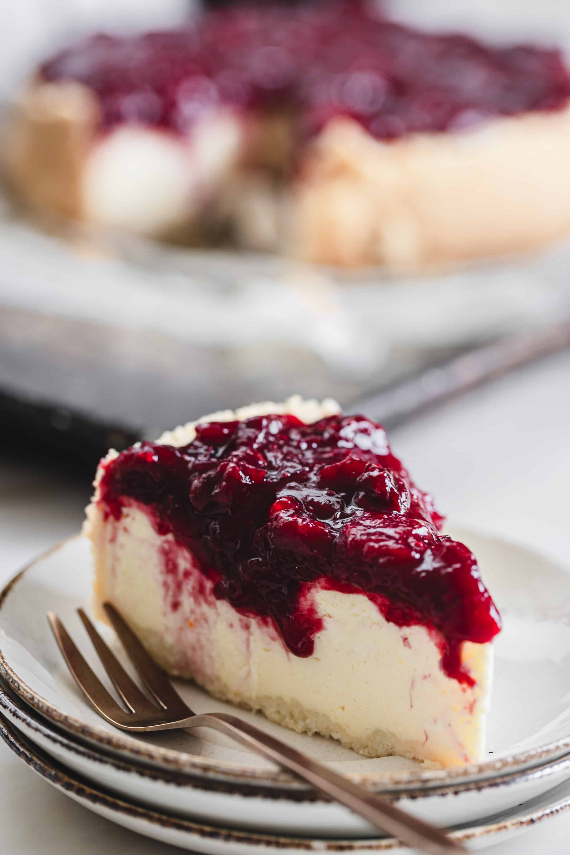 a slice of cheesecake with cranberry topping on a plate