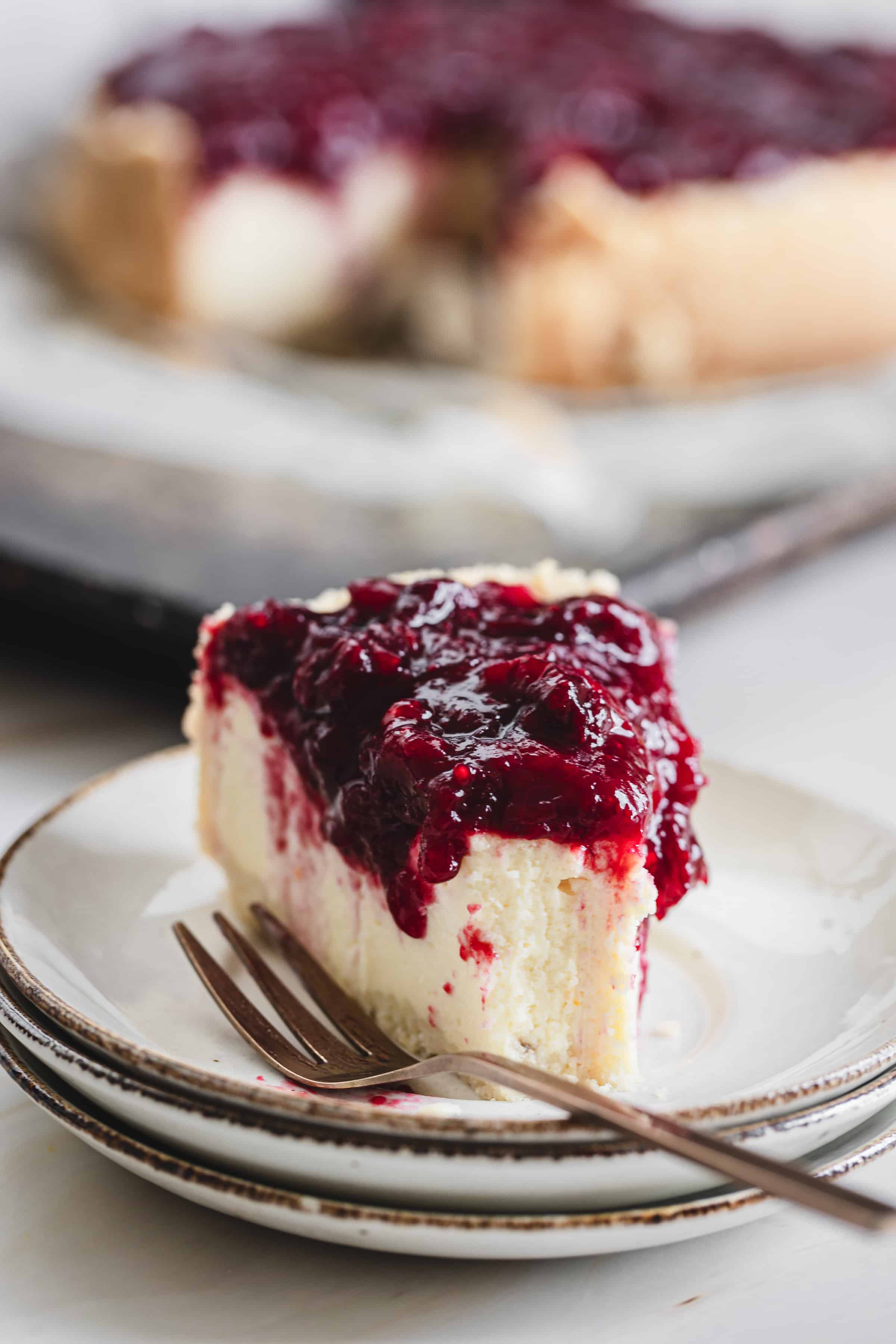 slice of cheesecake on a plate with cranberry topping