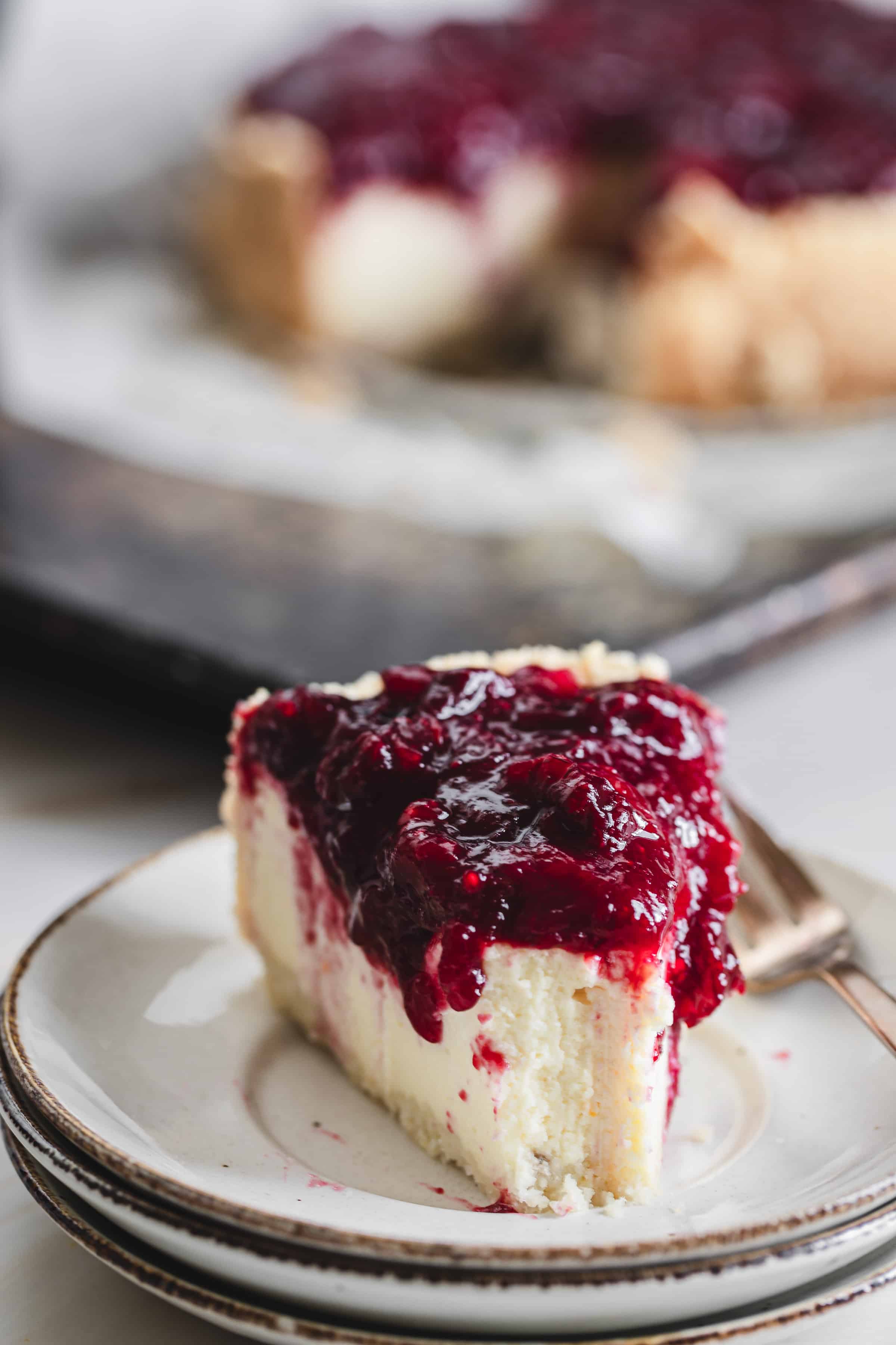 a slice of cheesecake with cranberry topping on a plate