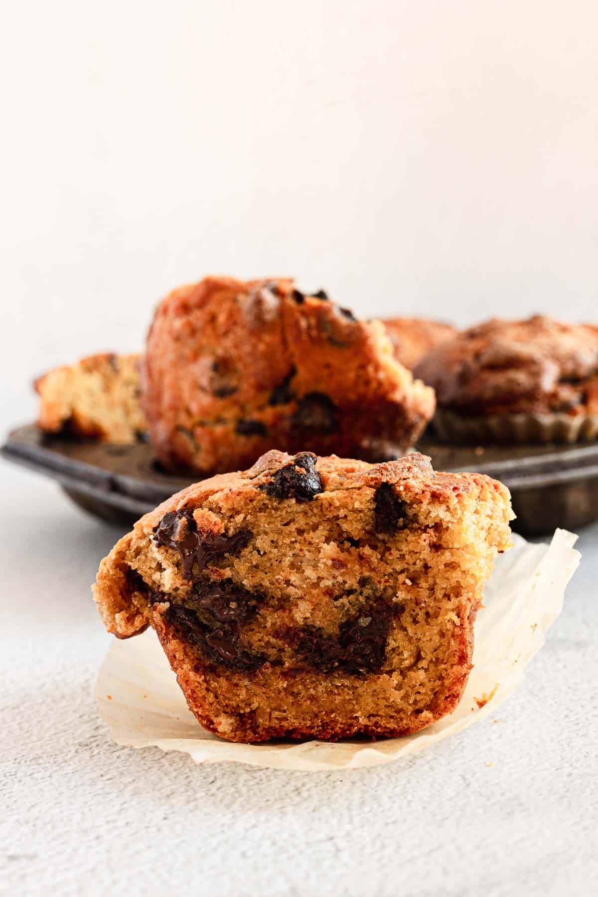 close up on gluten free chocolate chip muffin half with muffins in background