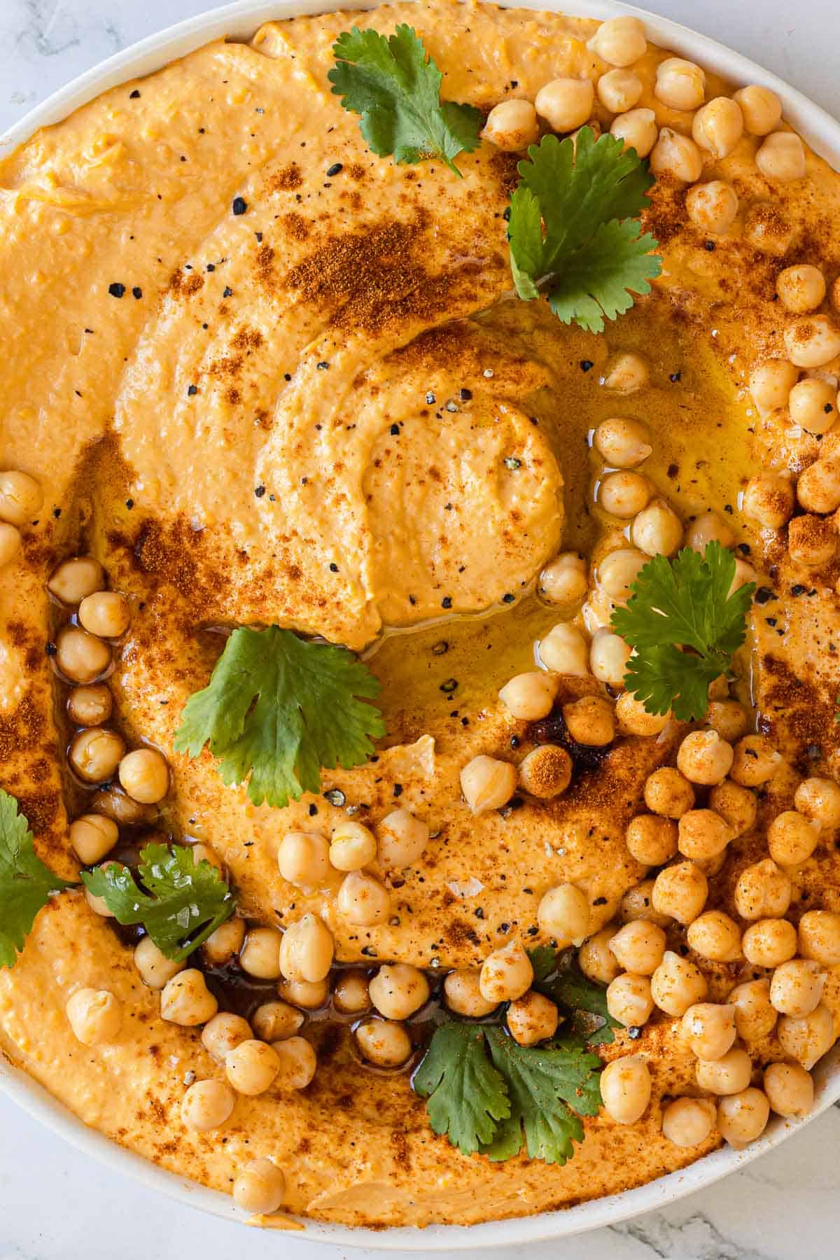 Overhead and close up view of a freshly garnished dish of sweet potato hummus.