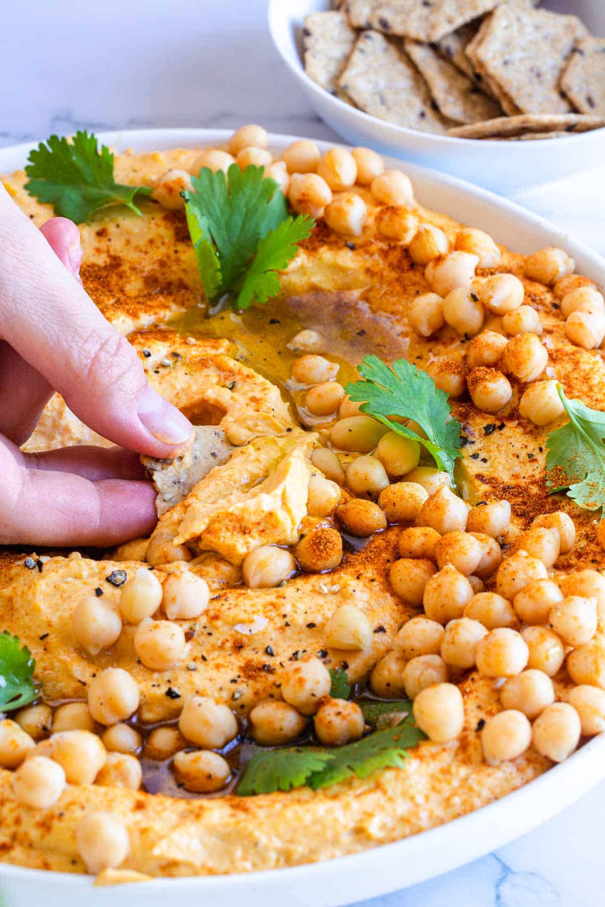 Close up side shot of a freshly garnished dish of sweet potato hummus.