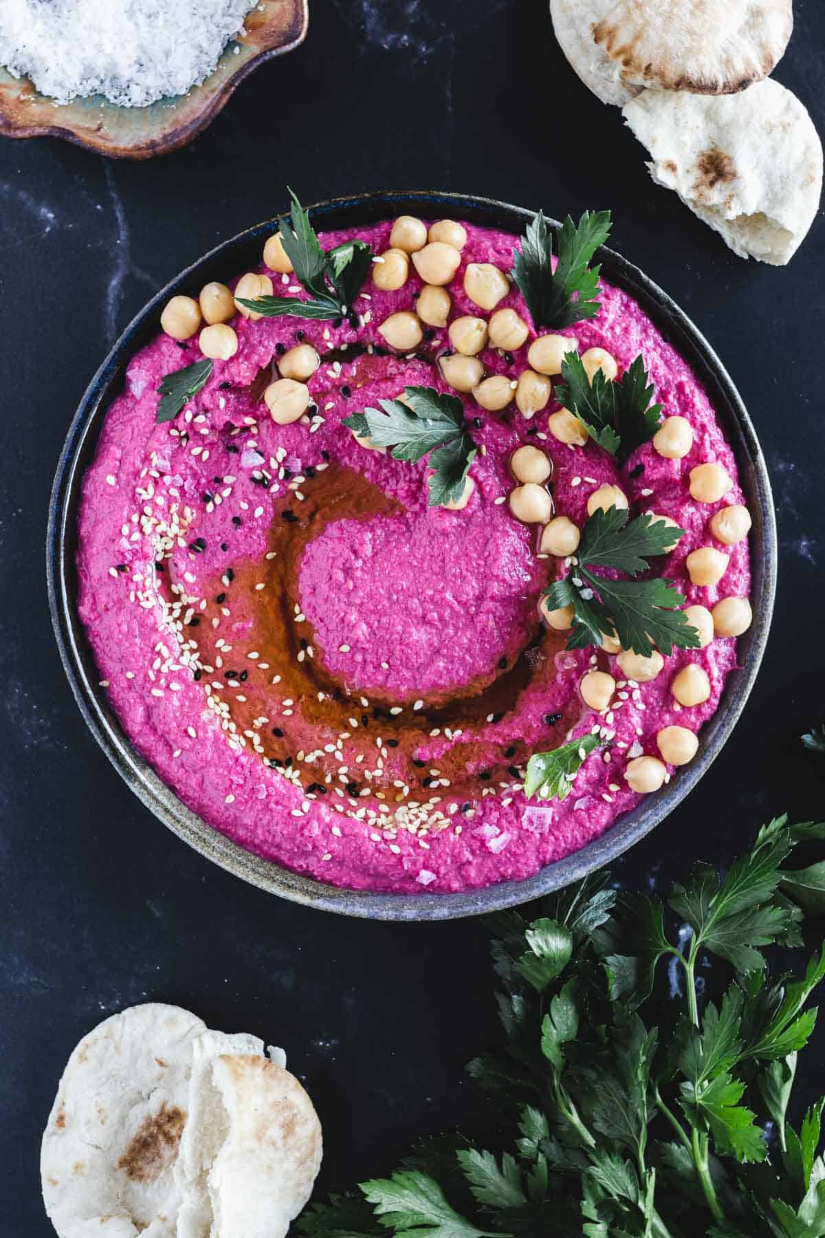 Seasoned and garnished beet hummus in a bowl.