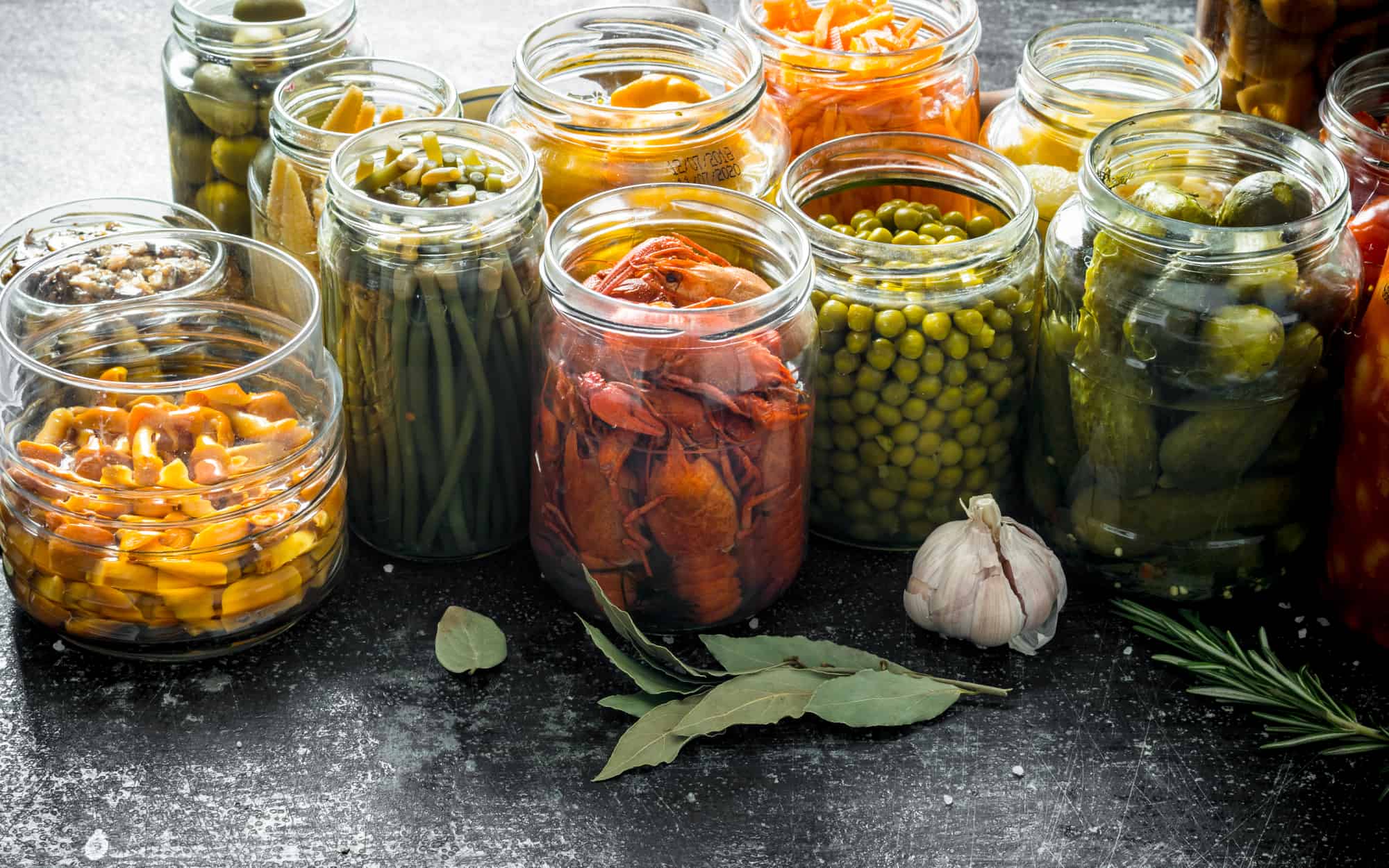 Composition with jars of pickled food. On dark rustic background