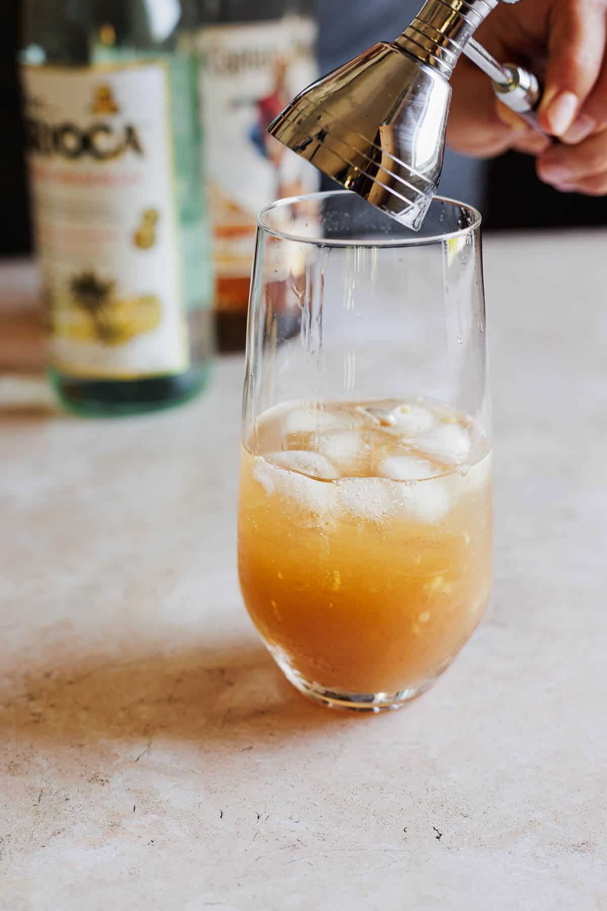 Ingredients being added to an ice filled glass.