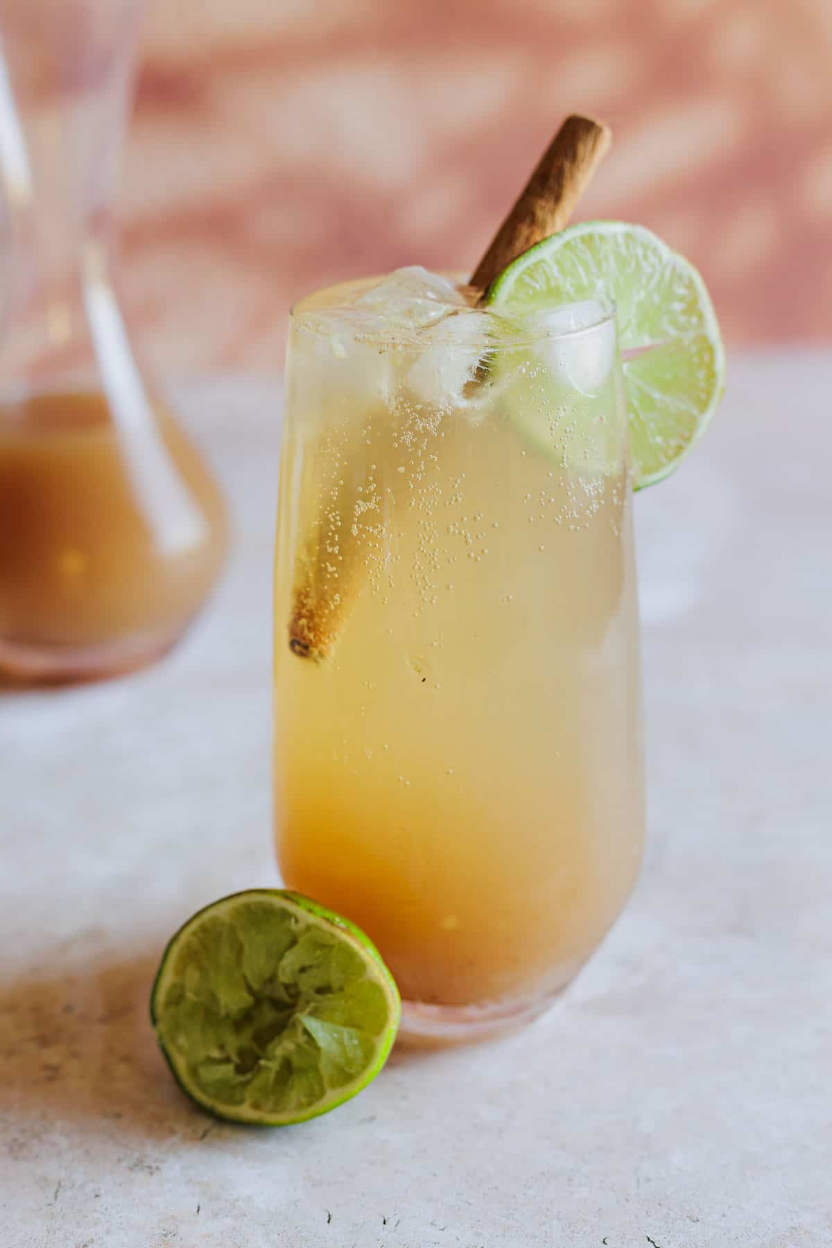 Tamarind cocktail garnished with a cinnamon stick and a lime wheel.