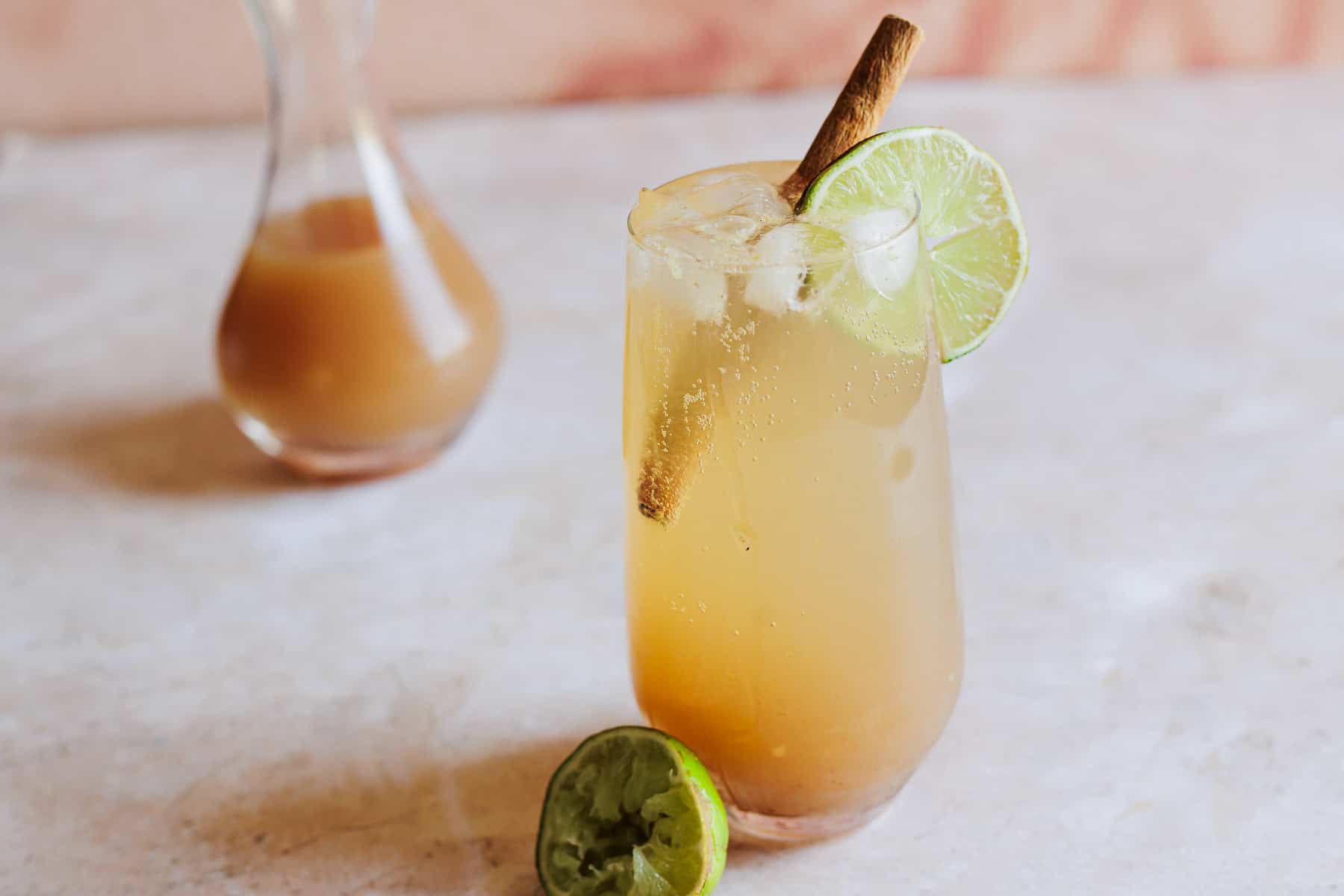 Tamarind cocktail garnished with a cinnamon stick and a lime wheel.