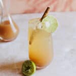 Tamarind cocktail garnished with a cinnamon stick and a lime wheel.