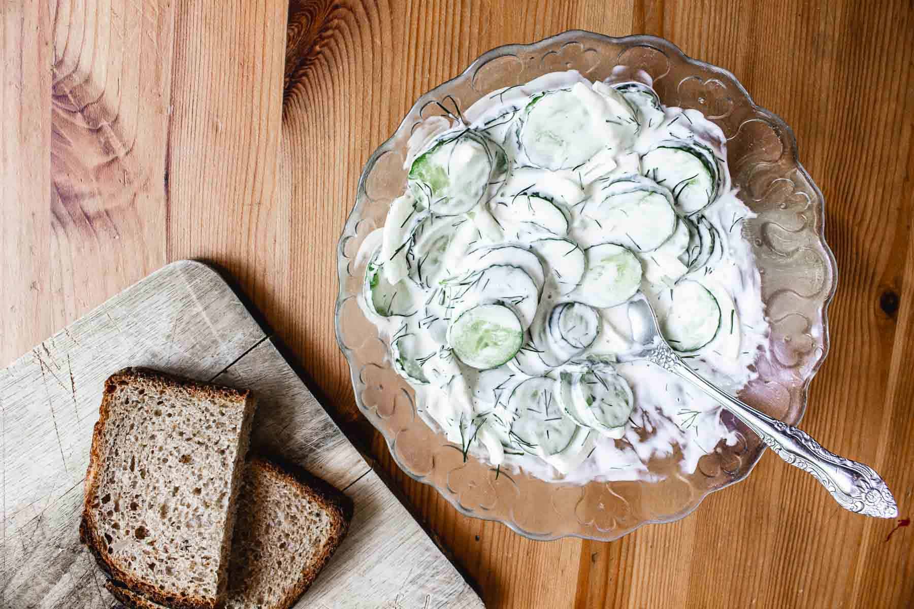 A bowl of cucumber salad with bread.