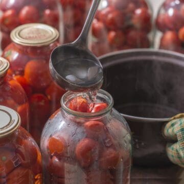 Canning tomatoes in jars with a spoon.