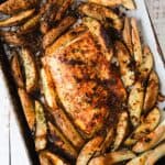A baking sheet with a piece of fish and potatoes.