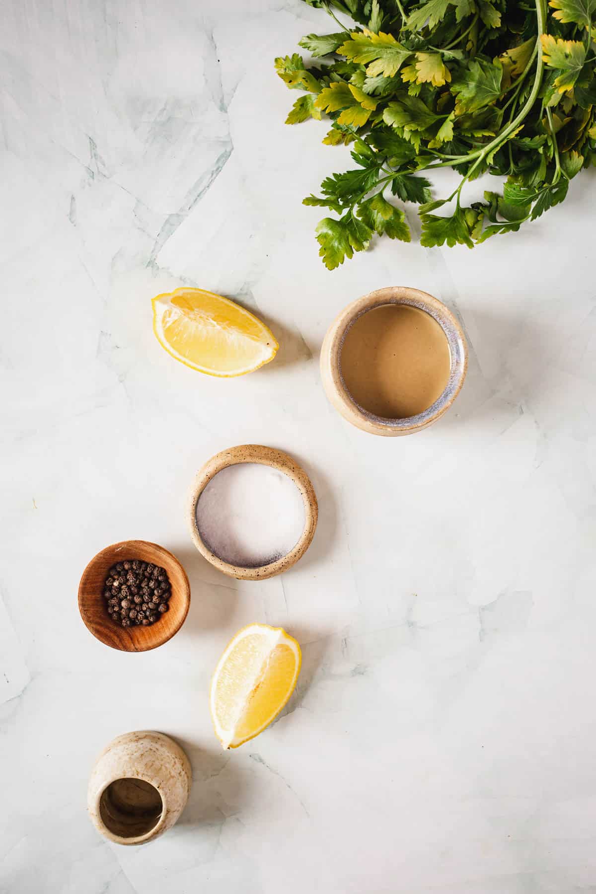 A bowl of lemon, parsley, and parmesan on a marble table.