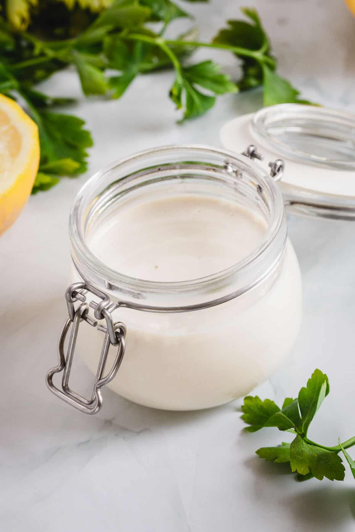 A jar of yogurt with lemons and parsley.