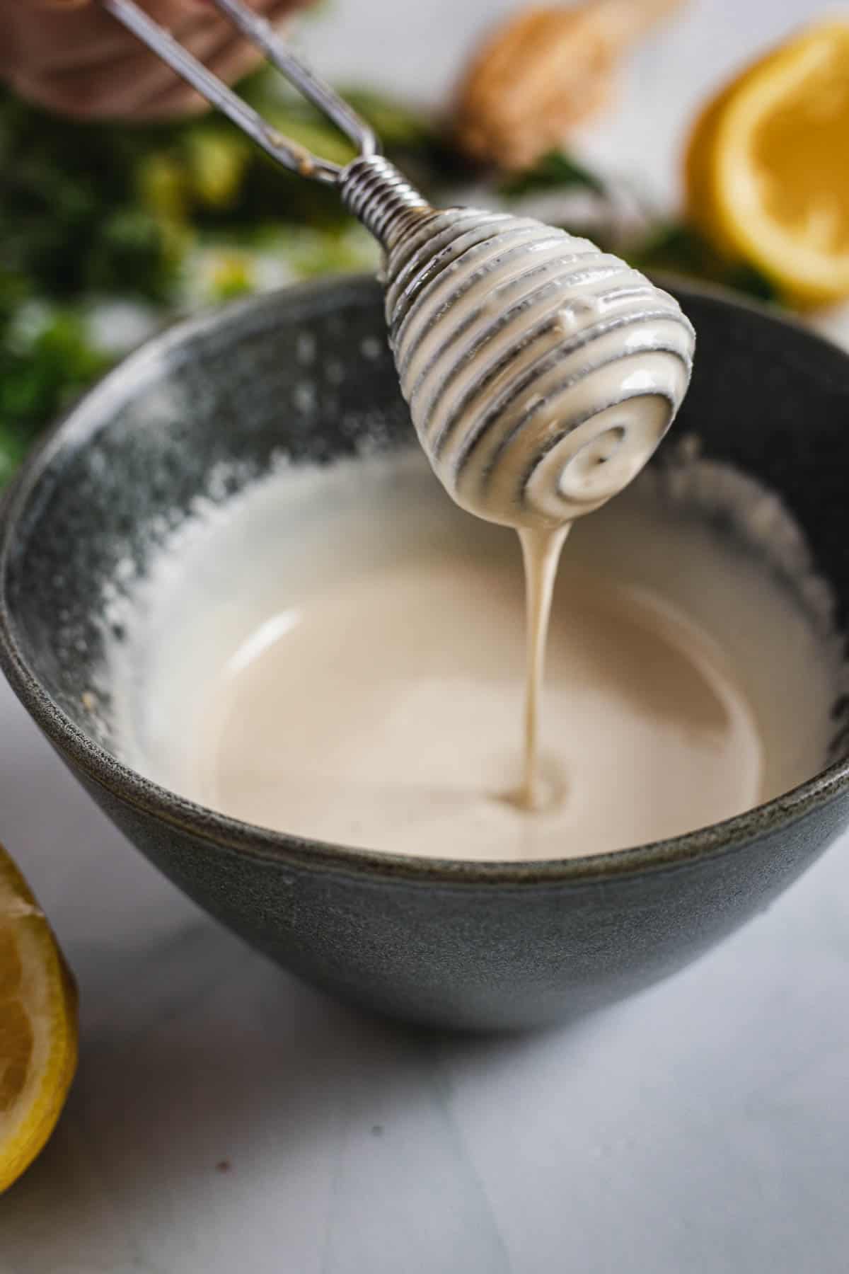 A person pouring honey into a bowl with lemons.