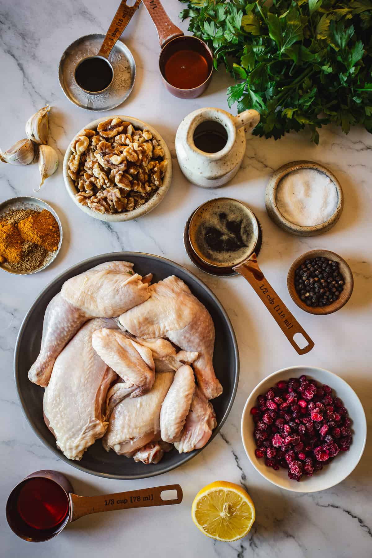 Roasted chicken with pomegranates and ingredients on a marble table.