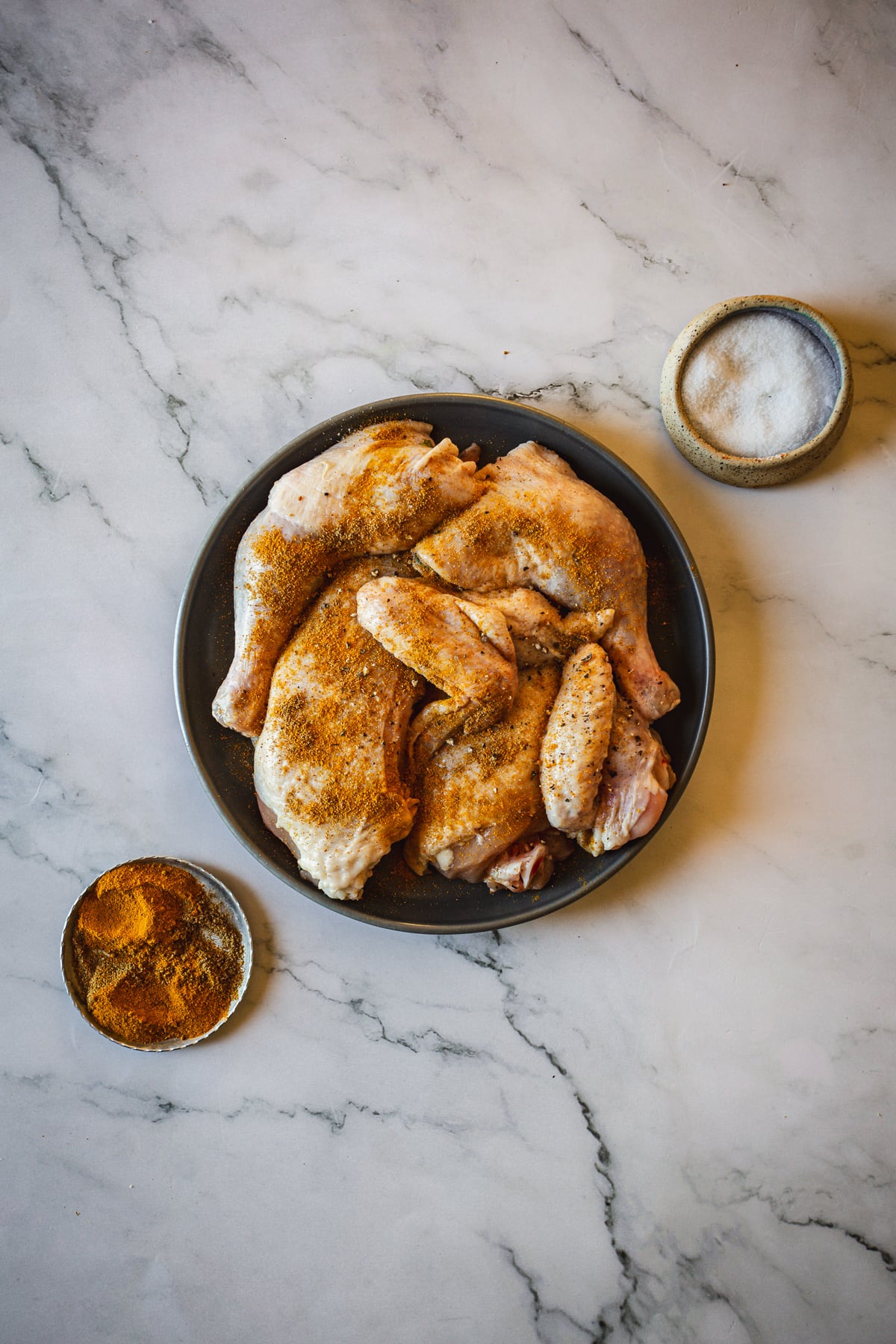 Raw chicken on a plate on a marble table.