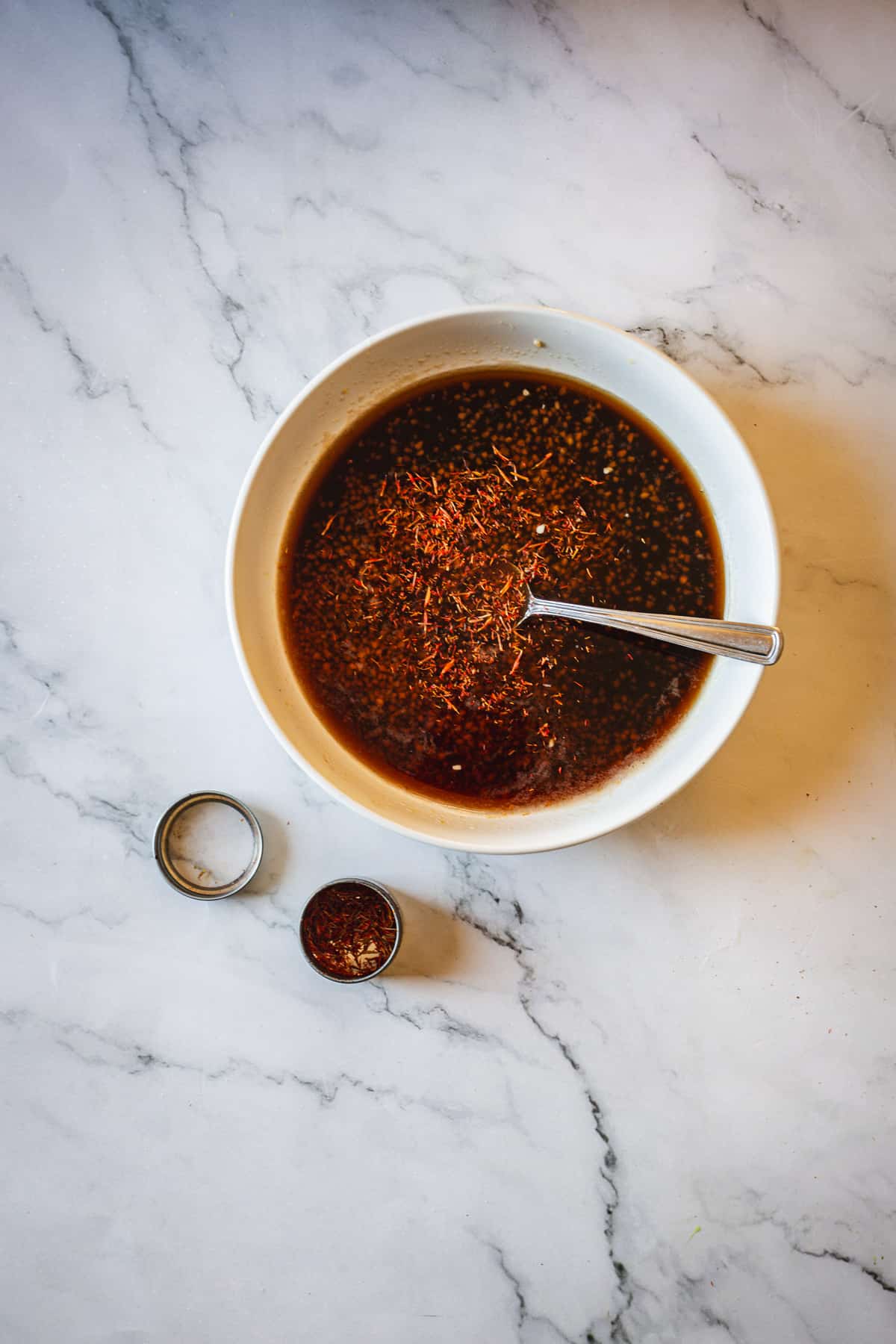 A bowl of sauce with a spoon next to it.