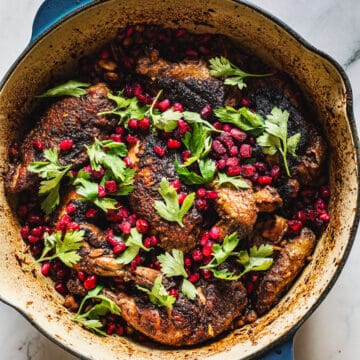 Roasted chicken with pomegranate and parsley in a skillet.