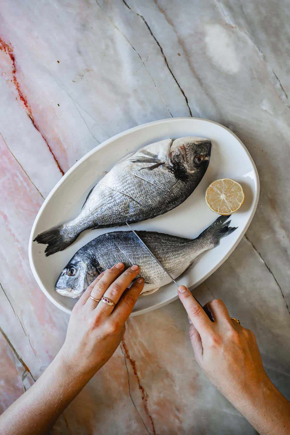 Two fish on a platter, being cut.