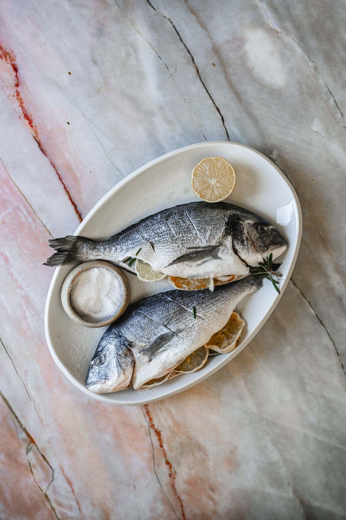 Two raw fish on a white platter.