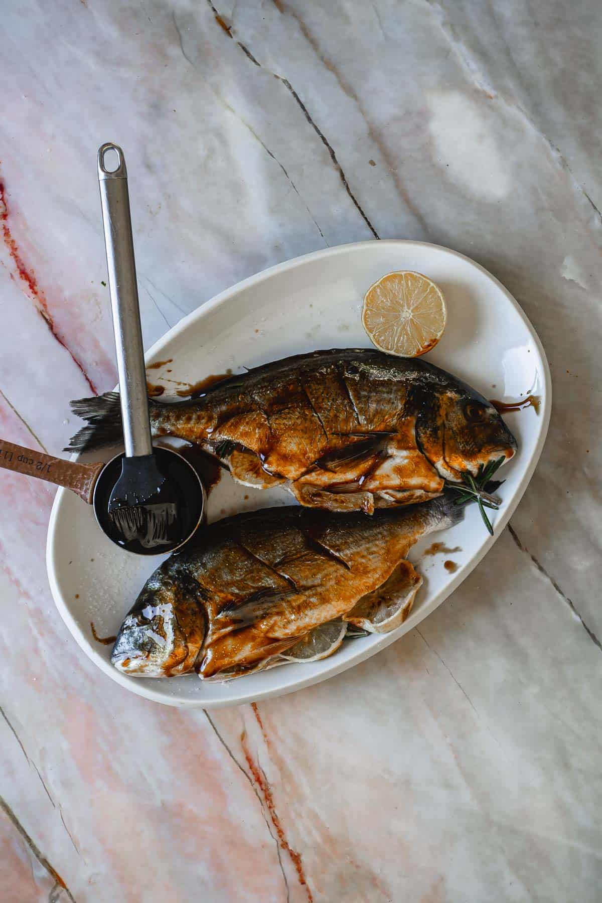 Raw whole fish covered in pomegranate sauce.