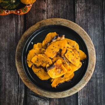 Roasted butternut squash on a black plate.