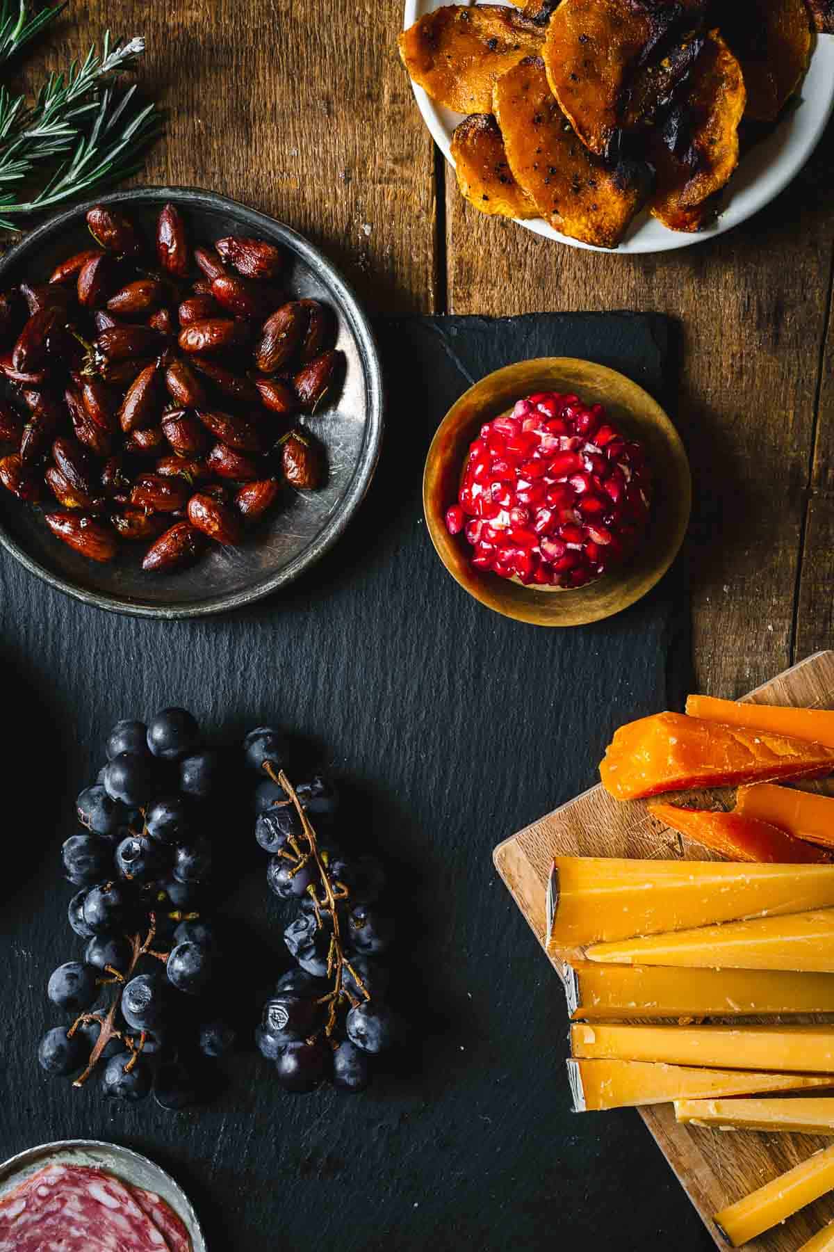 A platter of cheese, nuts, grapes and grapes on a table.