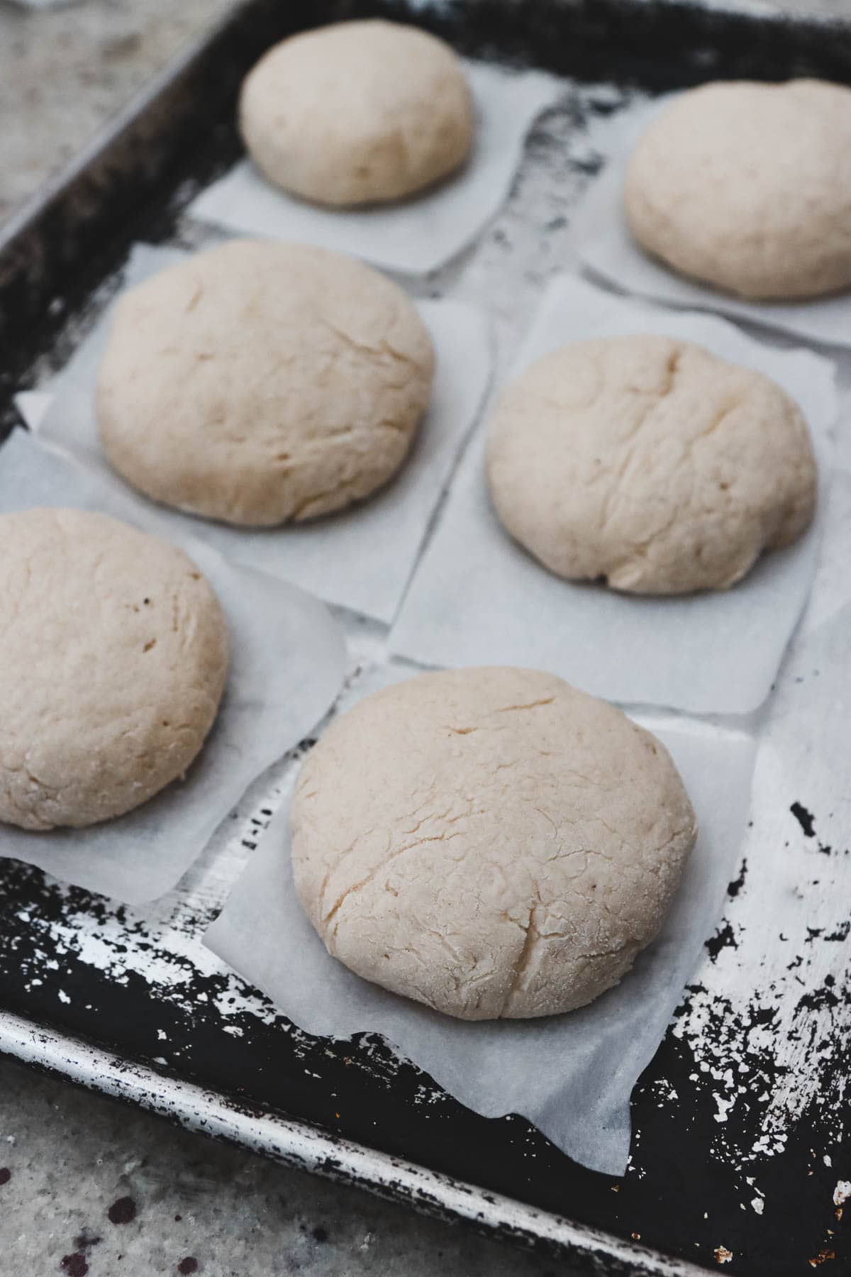 A baking sheet with several dough balls on it.