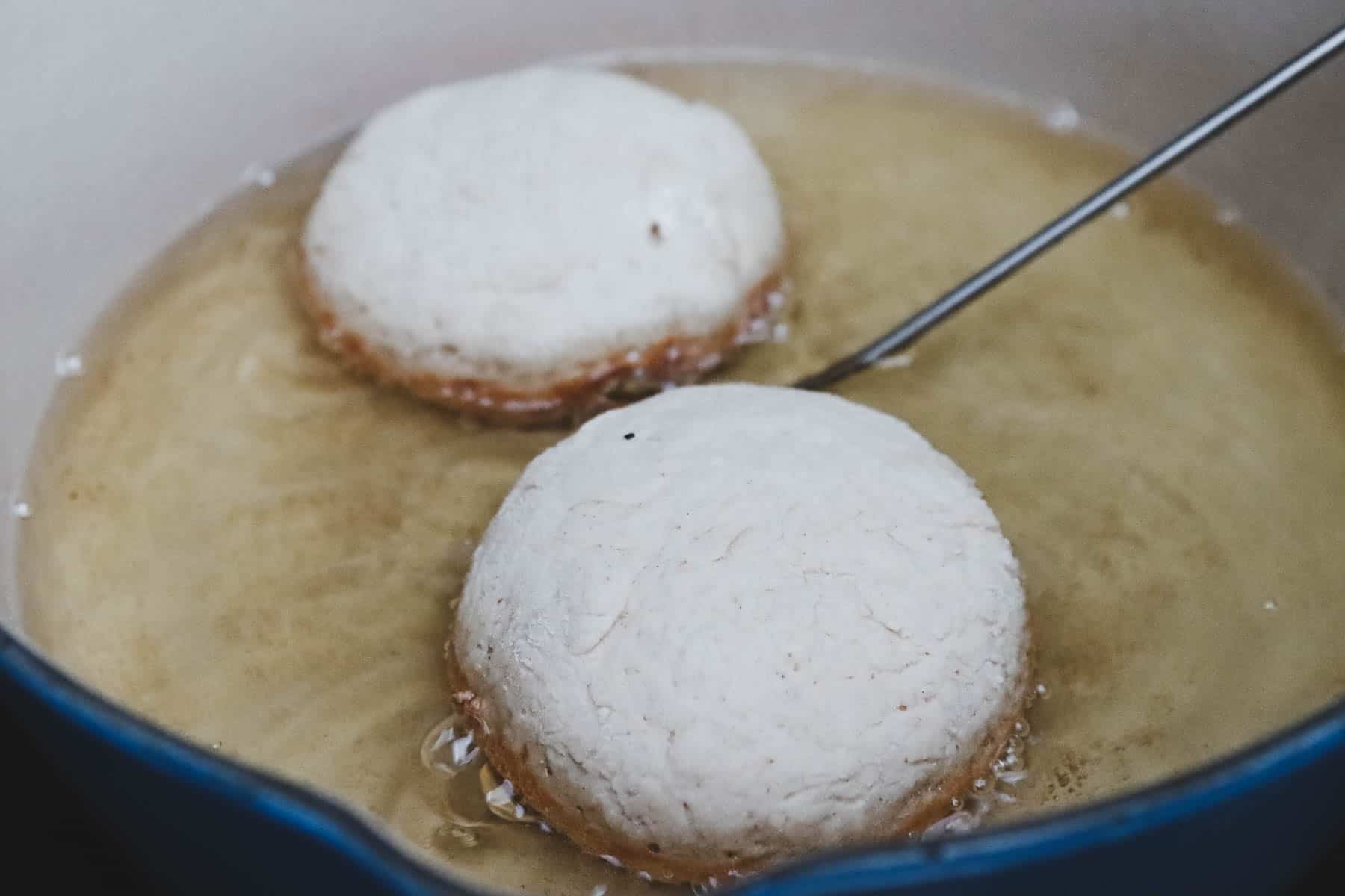 Two balls of dough being cooked in a dutch oven pot.