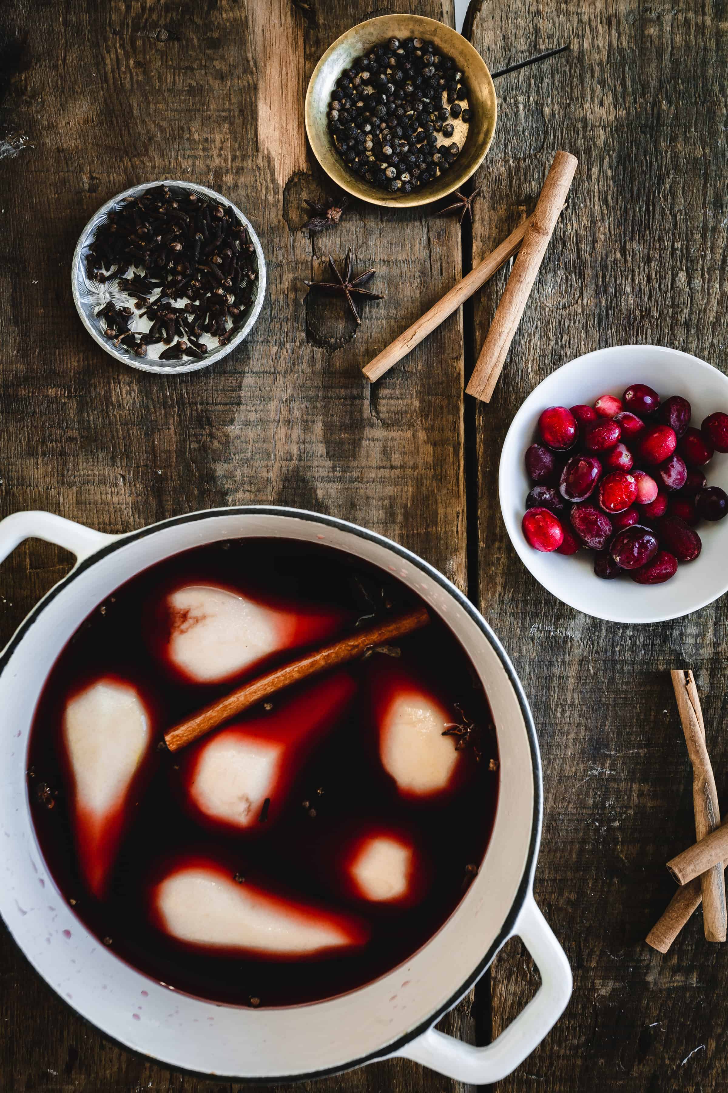 A bowl of mulled wine with cinnamon sticks and cranberries.