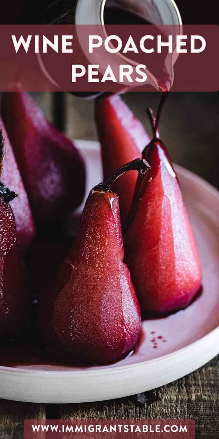 A close-up of wine poached pears on a white plate. The deep red pears glisten with syrup being poured over them. The top of the image features the text "Wine Poached Pears" and the bottom has a URL "www.immigrantstable.com".