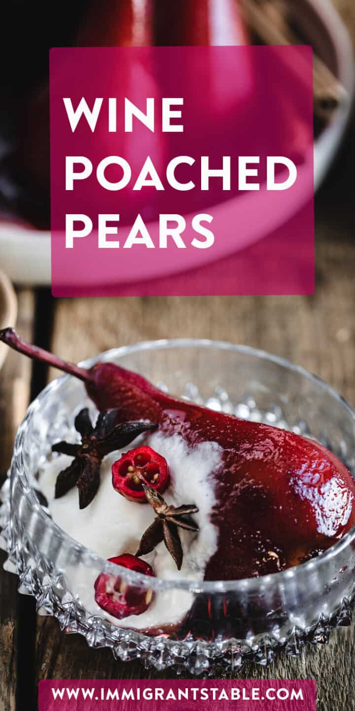 A close-up of a wine-poached pear served in a decorative glass bowl. The pear is garnished with star anise and a few cranberries or pomegranate seeds, placed on a wood surface. Text on the image reads "Deliciously Wine Poached Pears" with a website link at the bottom.