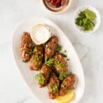kofta kebabs with tzatziki sauce on a white plate.