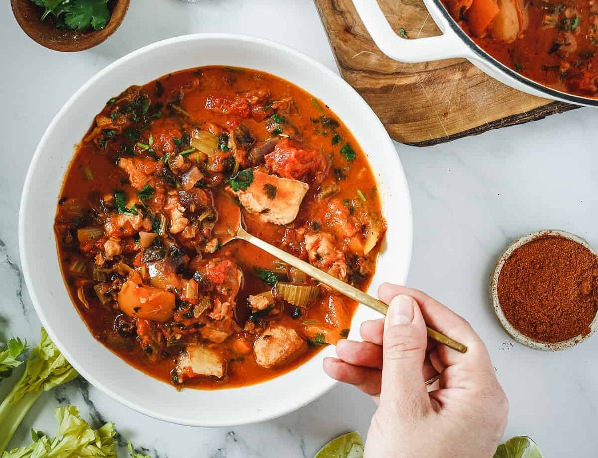 A bowl of brazilian moqueca with a spoon in it.