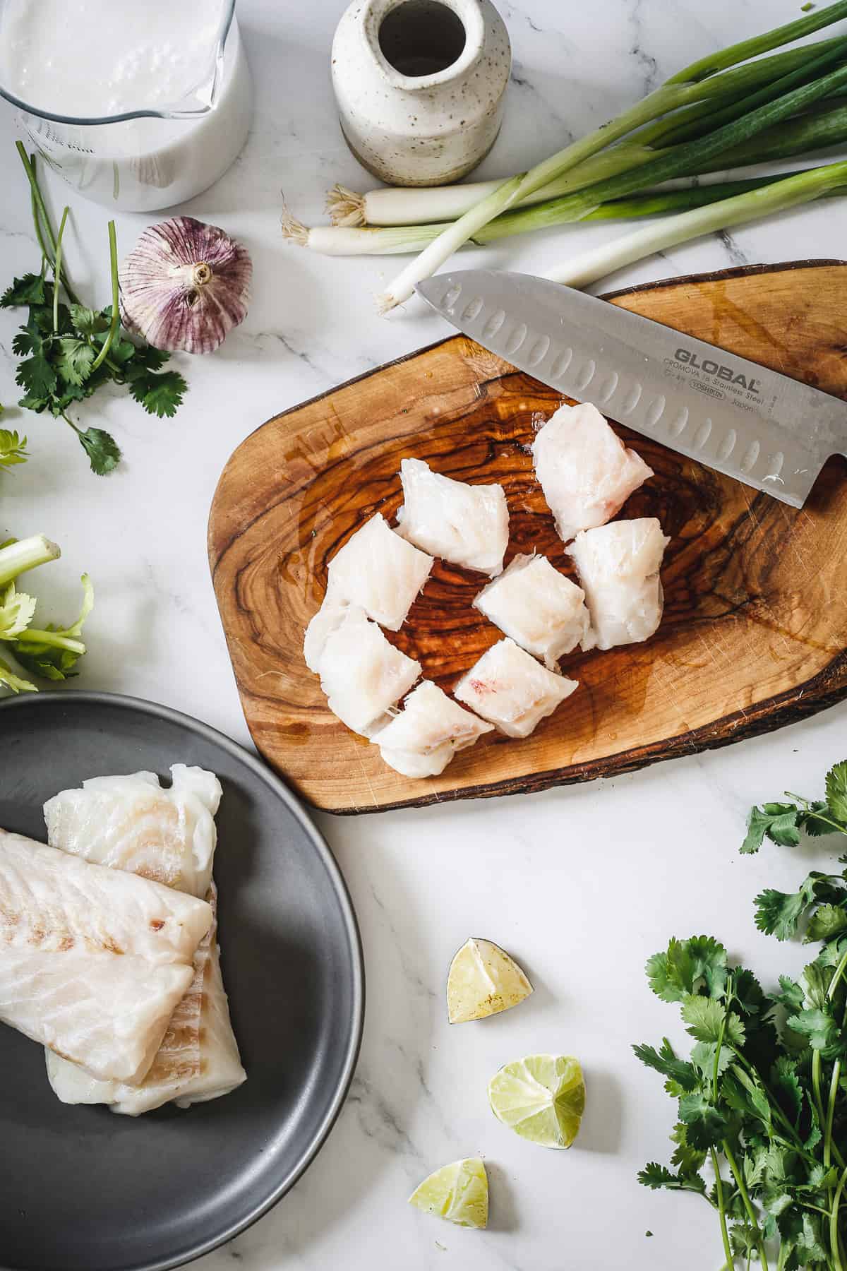 Fresh fish on a cutting board with limes and herbs.