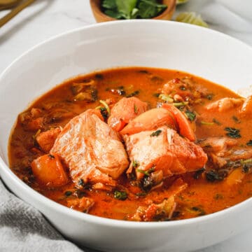 A bowl of stew with halibut in it.