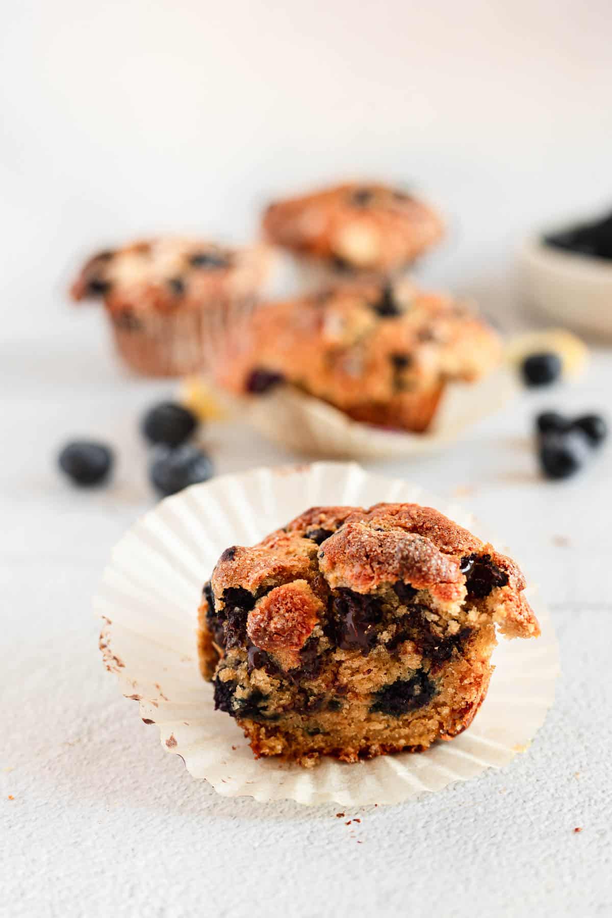 Blueberry muffins on a white plate with blueberries.