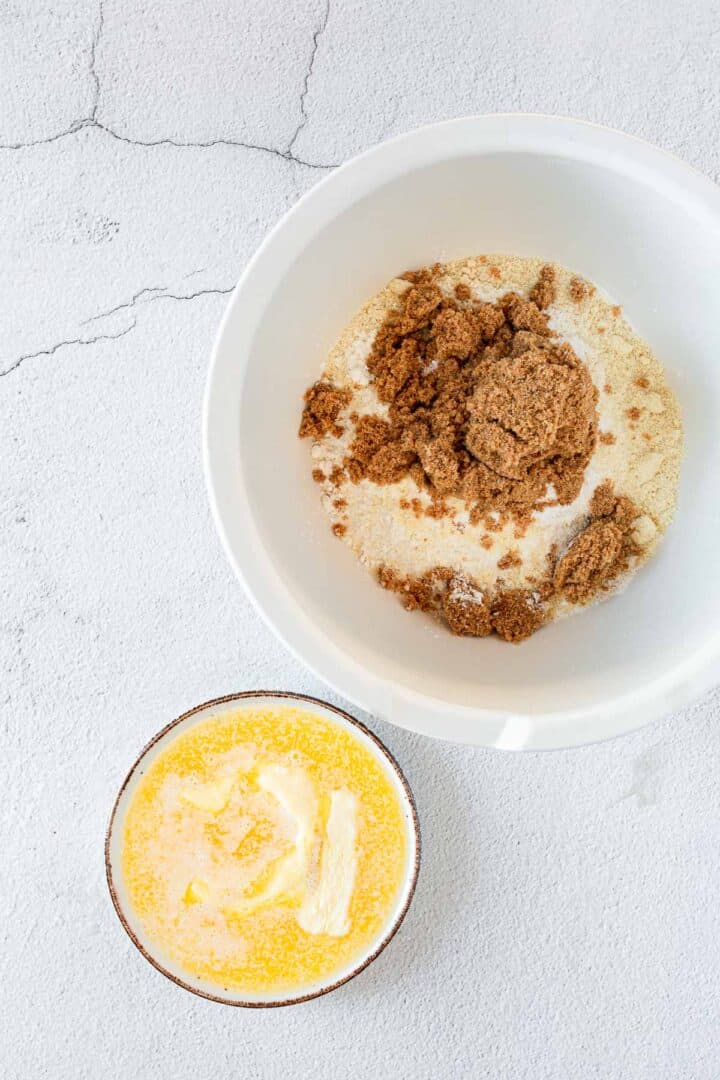 A bowl of gluten free blueberry ingredients next to a bowl of butter.